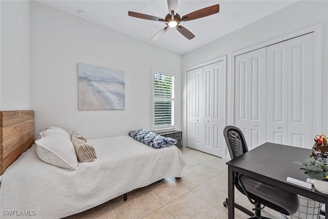 bedroom with light tile patterned floors, ceiling fan, and multiple closets