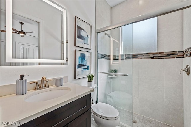 full bath with a stall shower, toilet, vanity, and a ceiling fan