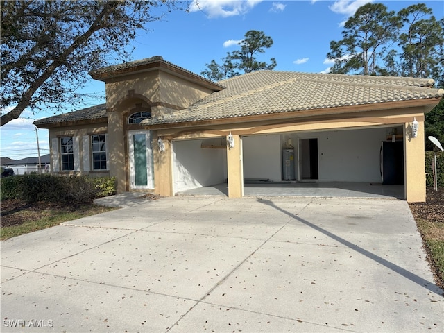 view of front of property featuring concrete driveway, a tiled roof, and water heater