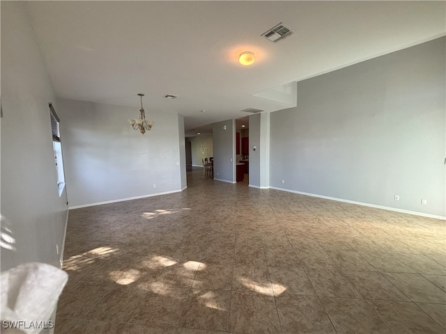 spare room featuring a chandelier, visible vents, and baseboards