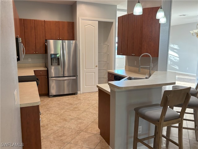 kitchen with a breakfast bar area, a peninsula, a sink, light countertops, and appliances with stainless steel finishes