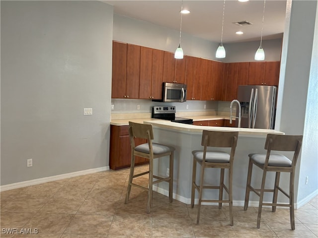 kitchen with pendant lighting, a kitchen breakfast bar, stainless steel appliances, and light countertops