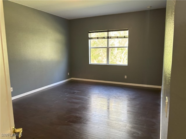 spare room featuring dark wood-style floors and baseboards