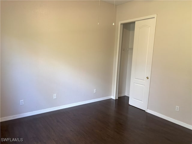 spare room with baseboards and dark wood-style flooring