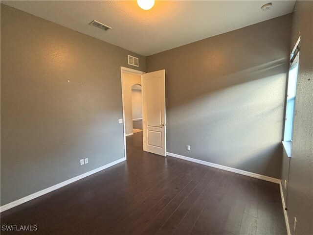 unfurnished room with dark wood finished floors, baseboards, and visible vents