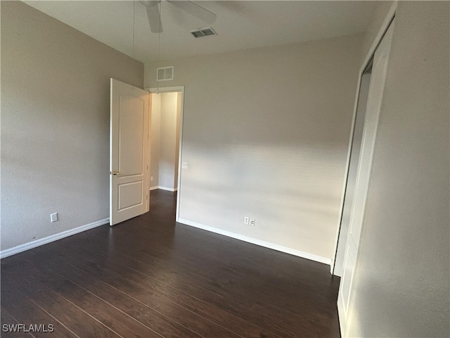 empty room featuring visible vents, baseboards, a ceiling fan, and dark wood-style flooring