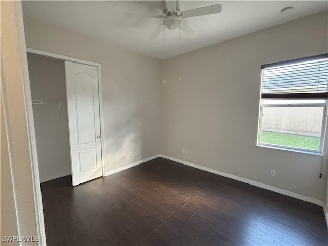 empty room featuring a ceiling fan, dark wood-style flooring, and baseboards