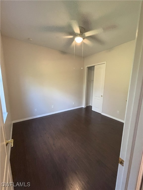 empty room with dark wood finished floors, a ceiling fan, baseboards, and a textured ceiling