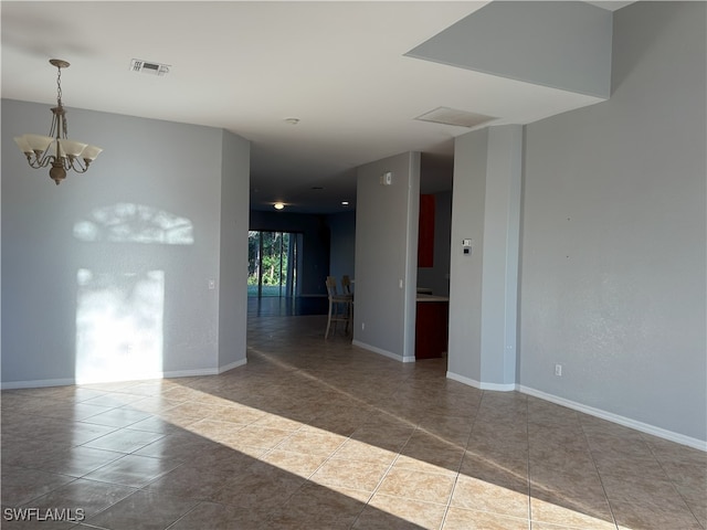 tiled empty room featuring a chandelier, visible vents, and baseboards