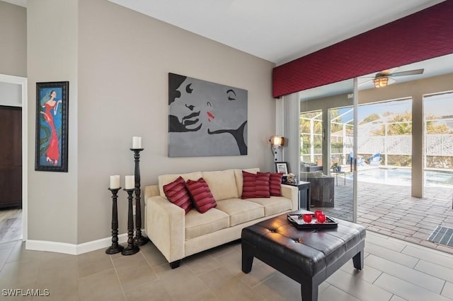 living room featuring tile patterned floors, baseboards, a ceiling fan, and a sunroom