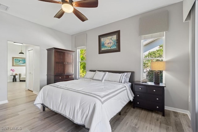 bedroom featuring light wood finished floors, visible vents, baseboards, and a closet