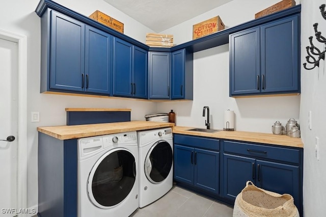 washroom with washing machine and clothes dryer, light tile patterned flooring, cabinet space, and a sink