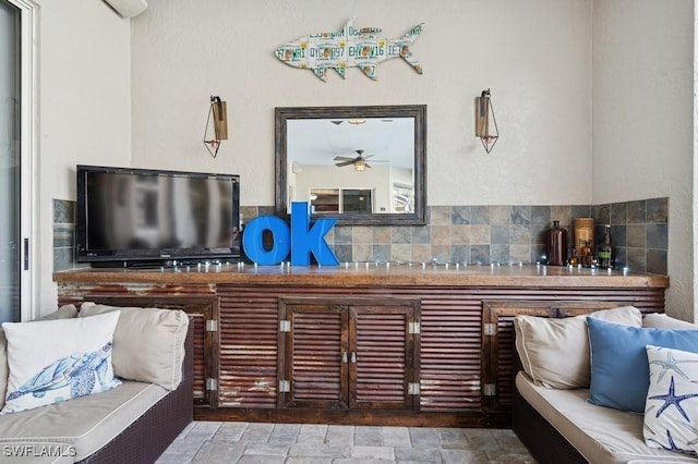 living area with stone finish flooring and ceiling fan