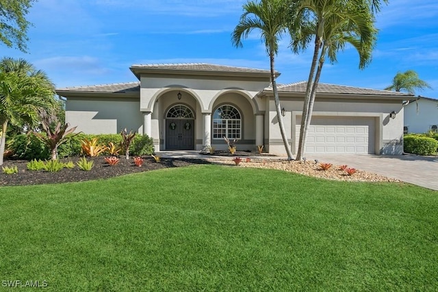 mediterranean / spanish-style home featuring a front yard, a garage, driveway, and stucco siding