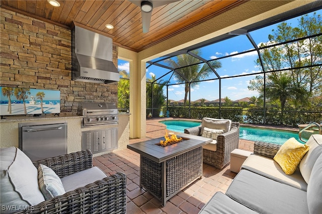 view of patio / terrace with a lanai, grilling area, an outdoor living space with a fire pit, and an outdoor kitchen