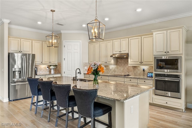 kitchen featuring under cabinet range hood, cream cabinets, appliances with stainless steel finishes, and a sink