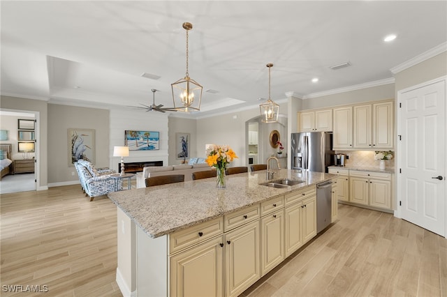 kitchen featuring stainless steel appliances, light wood-style floors, cream cabinets, ceiling fan with notable chandelier, and open floor plan