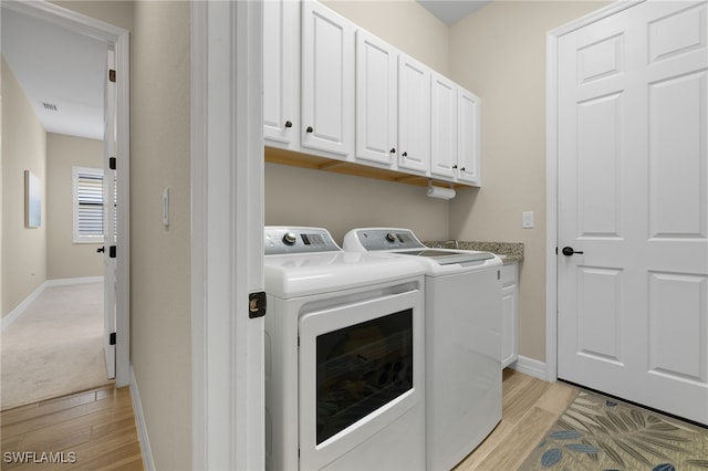 washroom featuring visible vents, light wood finished floors, baseboards, cabinet space, and independent washer and dryer