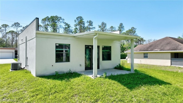 rear view of house featuring a patio, central air condition unit, a lawn, and stucco siding