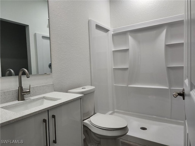 full bathroom featuring vanity, toilet, a shower stall, and a textured wall