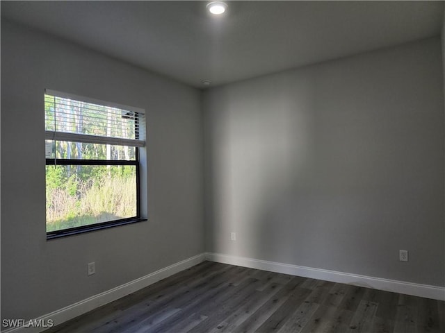 spare room featuring dark wood-type flooring and baseboards