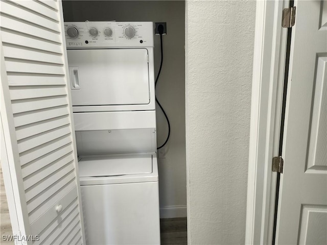 laundry room with laundry area, a textured wall, and stacked washing maching and dryer
