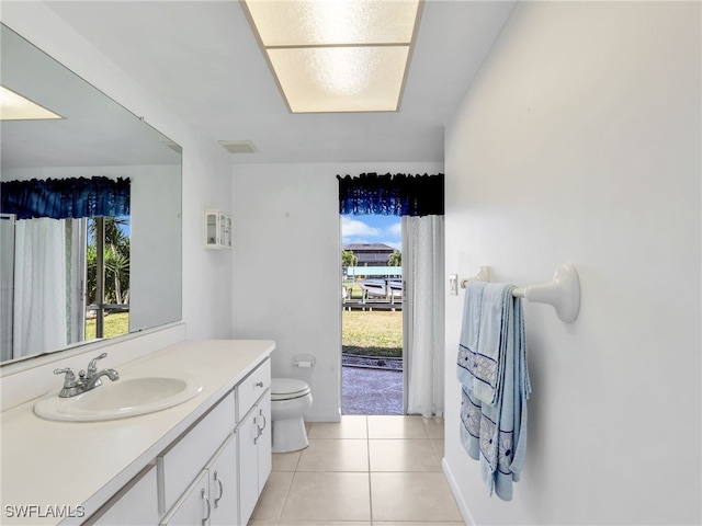 bathroom with toilet, vanity, and tile patterned flooring