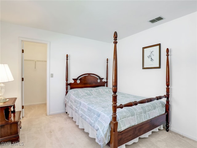 bedroom featuring visible vents, baseboards, light colored carpet, and a spacious closet