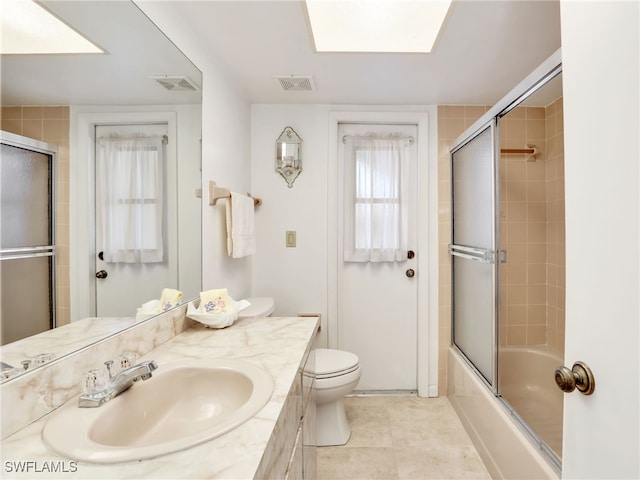 bathroom with visible vents, toilet, vanity, and shower / bath combination with glass door