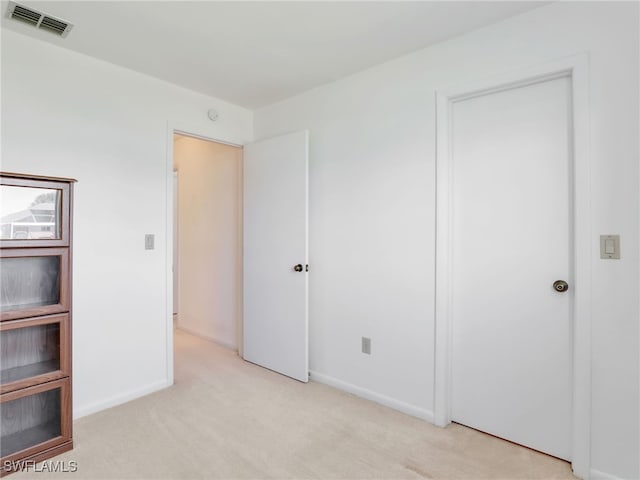 unfurnished bedroom with light carpet, visible vents, and baseboards