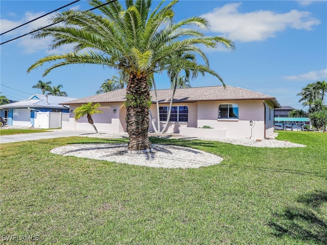 back of property with stucco siding, concrete driveway, a yard, and fence