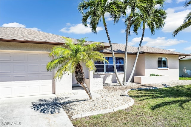 view of front of property with a front yard, an attached garage, a shingled roof, stucco siding, and concrete driveway