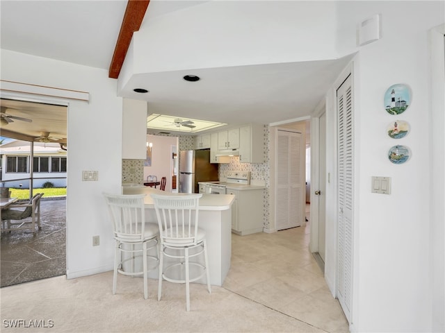 kitchen featuring a ceiling fan, under cabinet range hood, white electric range oven, freestanding refrigerator, and decorative backsplash