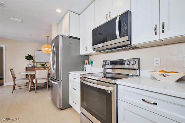 kitchen with visible vents, light countertops, appliances with stainless steel finishes, hanging light fixtures, and white cabinets