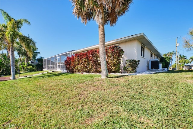 view of side of home featuring stucco siding, a lawn, and a lanai