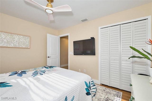 bedroom featuring visible vents, a closet, wood finished floors, and a ceiling fan