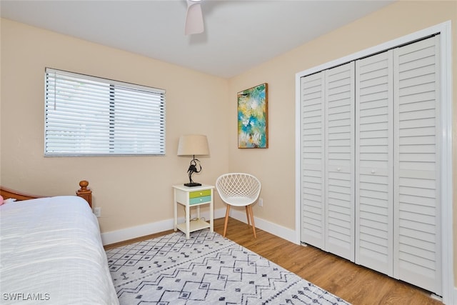 bedroom with wood finished floors, baseboards, a closet, and ceiling fan