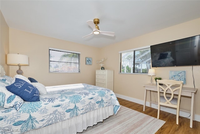 bedroom with a ceiling fan, wood finished floors, and baseboards