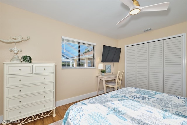 bedroom featuring visible vents, ceiling fan, baseboards, wood finished floors, and a closet