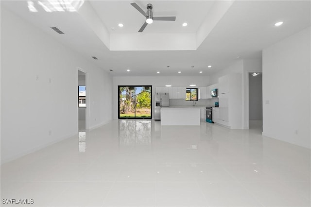 unfurnished living room featuring a tray ceiling, recessed lighting, a ceiling fan, and visible vents