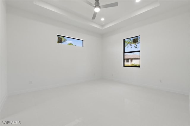 empty room featuring a ceiling fan, a raised ceiling, recessed lighting, and baseboards