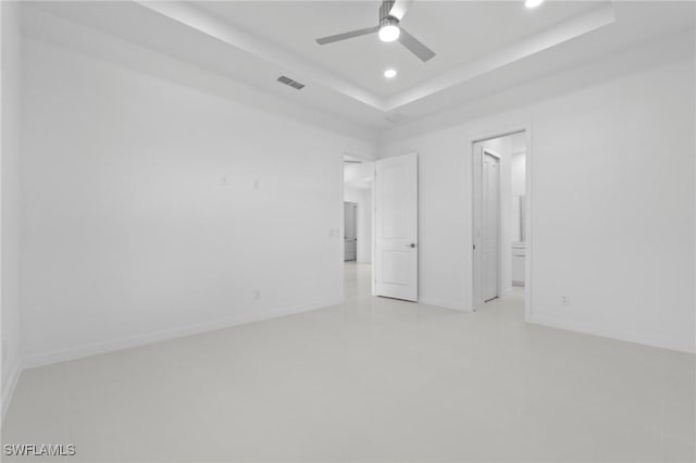 empty room featuring visible vents, a ceiling fan, a tray ceiling, recessed lighting, and baseboards