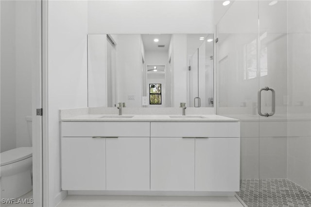 full bath featuring a sink, toilet, double vanity, and a shower stall