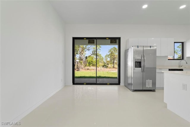 kitchen featuring recessed lighting, stainless steel fridge with ice dispenser, light countertops, white cabinetry, and modern cabinets