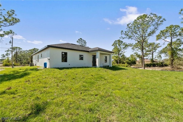 rear view of house with stucco siding and a lawn