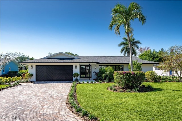 view of front facade featuring a garage, decorative driveway, a front yard, and stucco siding