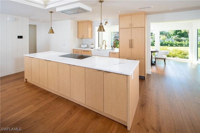 kitchen with wood finished floors, light brown cabinetry, a sink, a large island, and black electric stovetop