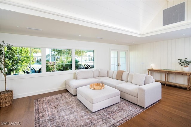 living area with visible vents, baseboards, wood finished floors, and vaulted ceiling