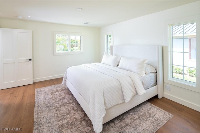 bedroom featuring multiple windows, baseboards, and wood finished floors