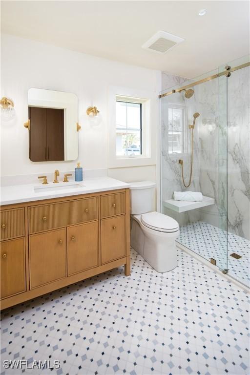 bathroom featuring vanity, toilet, visible vents, and a marble finish shower